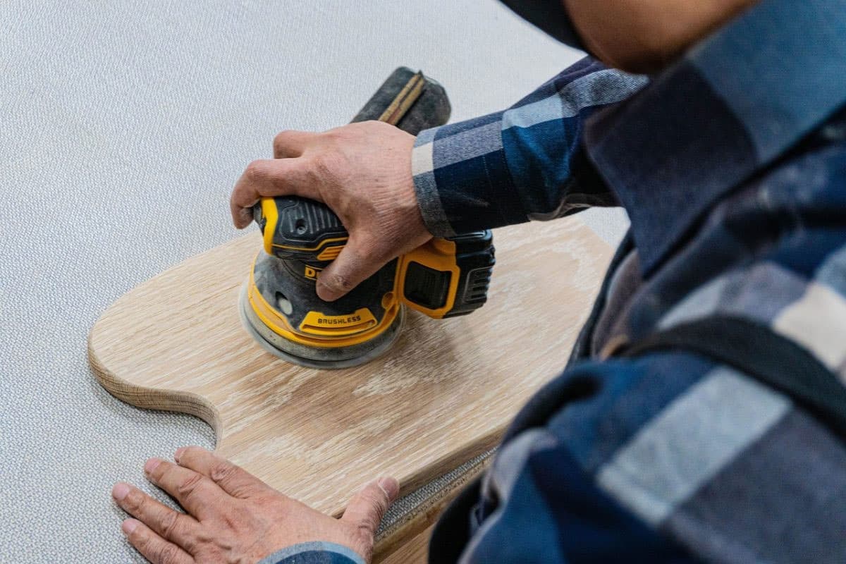 Proceso de lijado de un mueble de madera para preparar la superficie antes de pintar.