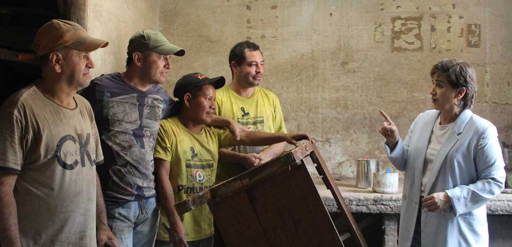 Lurdes en el taller de pintura habla con los artesanos.